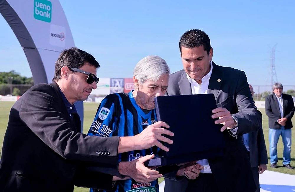 Robert Harrison, presidente de la APF, entrega un reconocimiento a Óscar Sosa